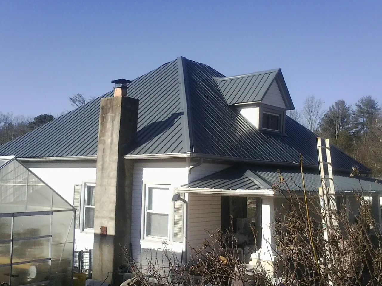 Dark blue standing seam metal roof on a white farmhouse with dormer — Slate & Tile Roof Repair by Roofing Brothers in Nicholls