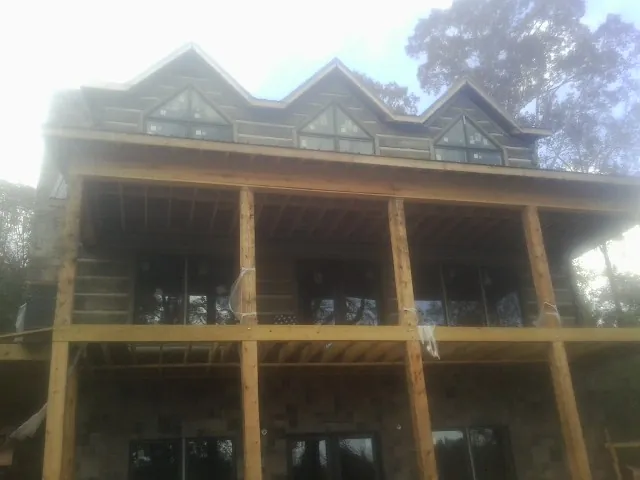 Dormers and porch framing on a large log home under construction — Roof Coating work by our crew in Nicholls