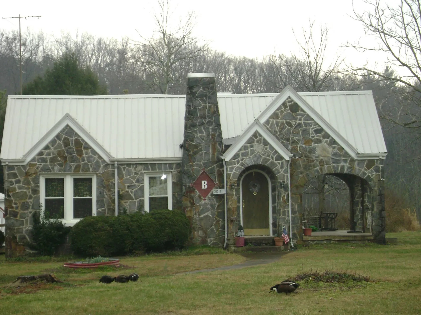 White metal roof on a stone cottage with steep gables in Nicholls
