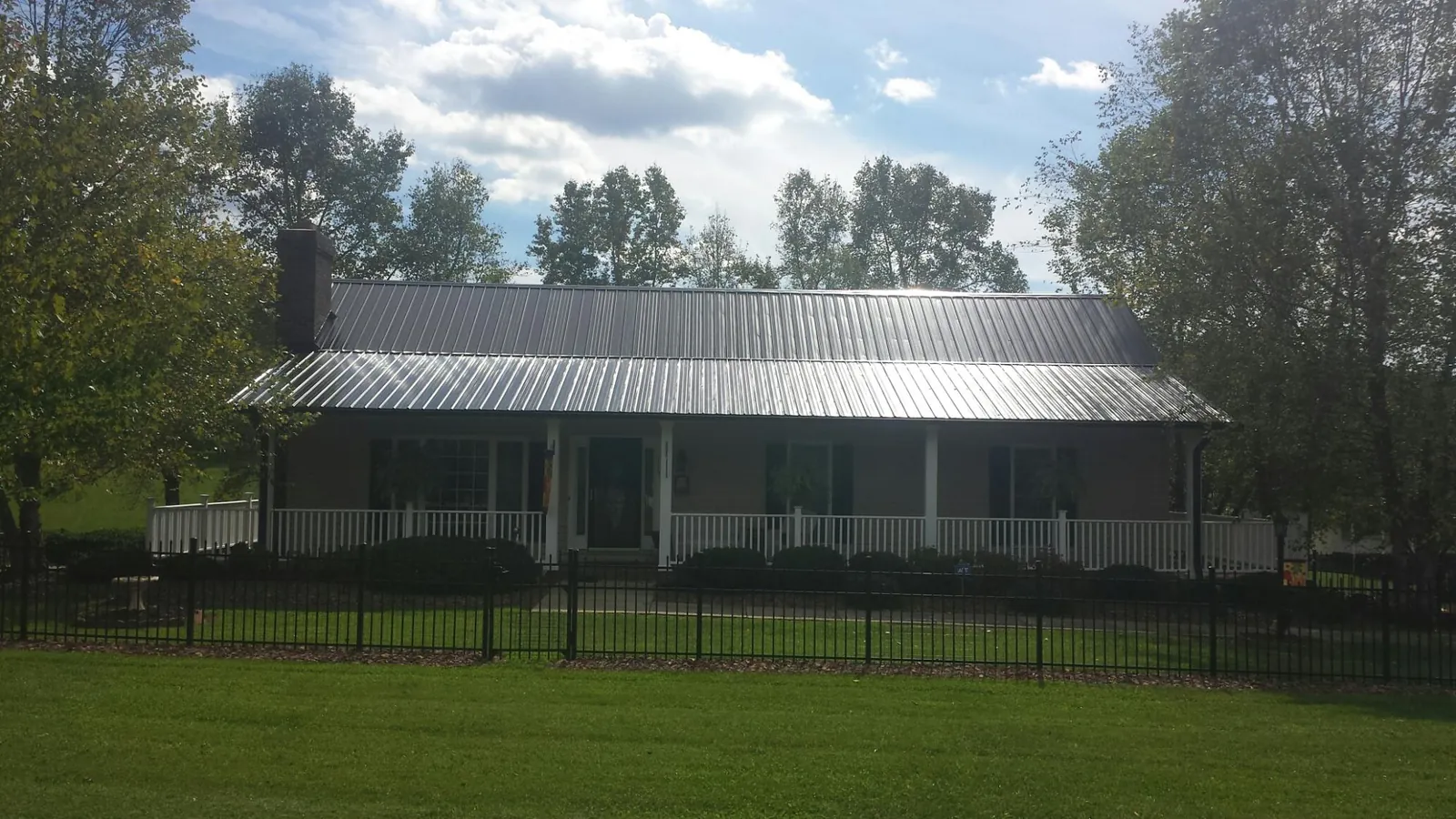 Gray metal roof on a brick ranch with a full width front porch — Gutter Guard Installation work by our crew in Nicholls