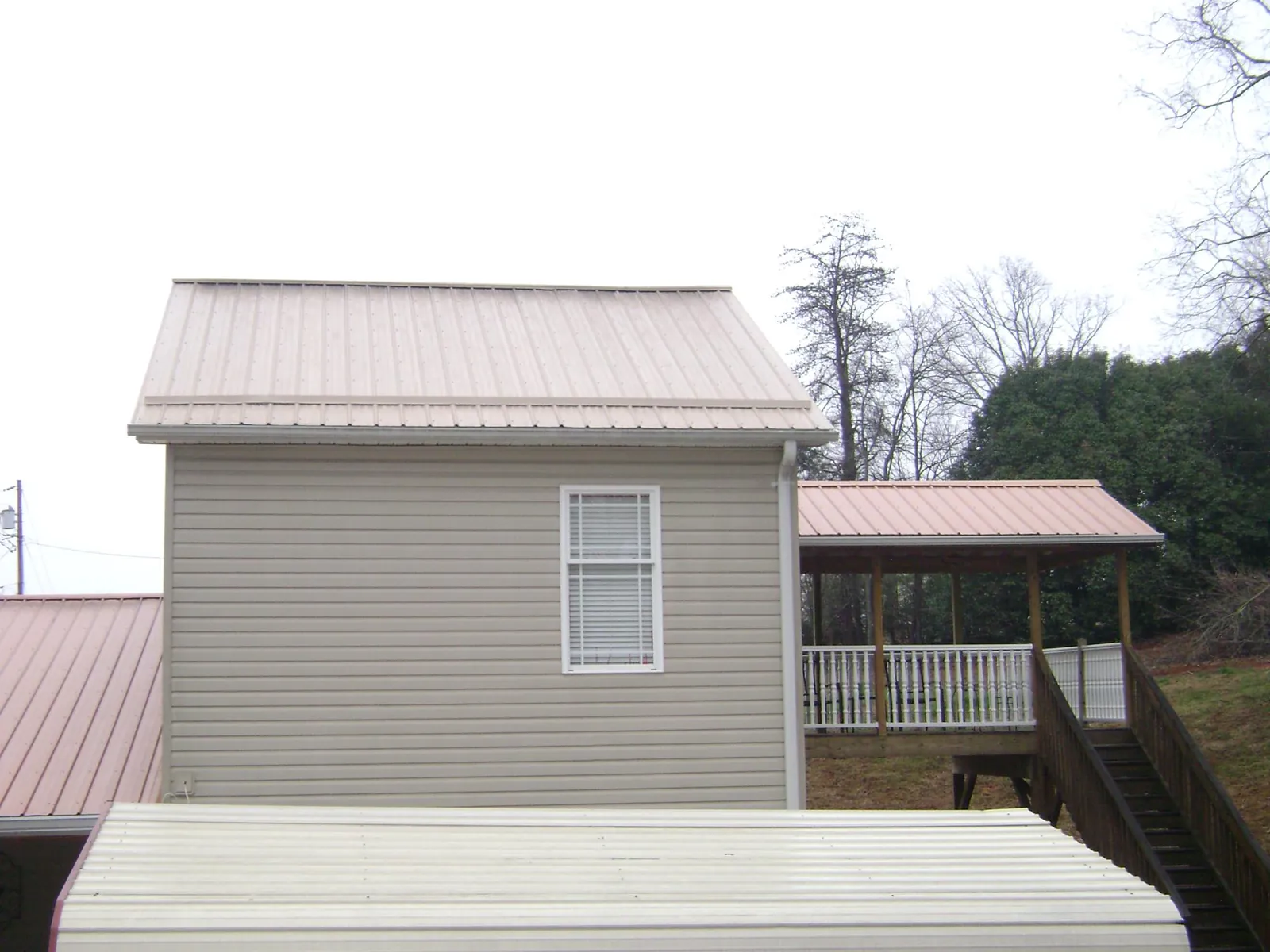 Tan metal roofs on a two story addition and attached porch, from a Roof Replacement job in Nicholls