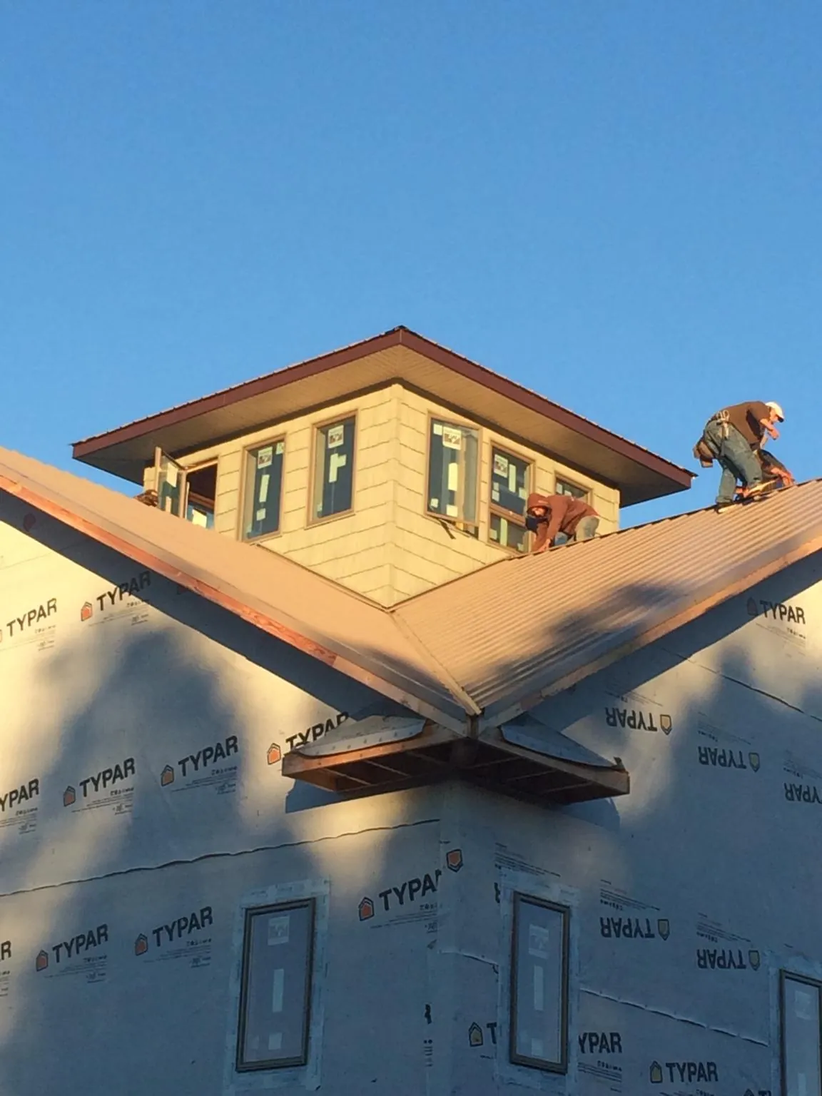 Roofers working around a rooftop cupola on a new metal roof at sunset — Roof Waterproofing in Nicholls by Roofing Brothers